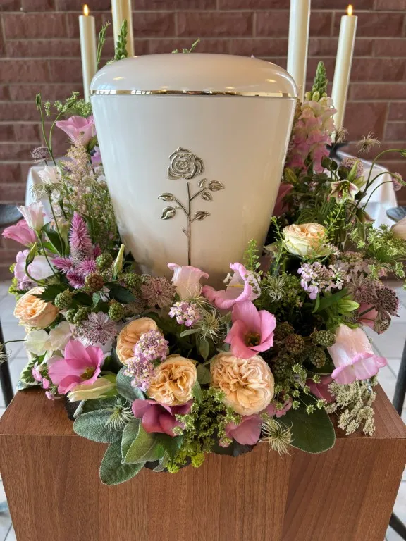 Urne umgeben von buntem Blumenstrauß