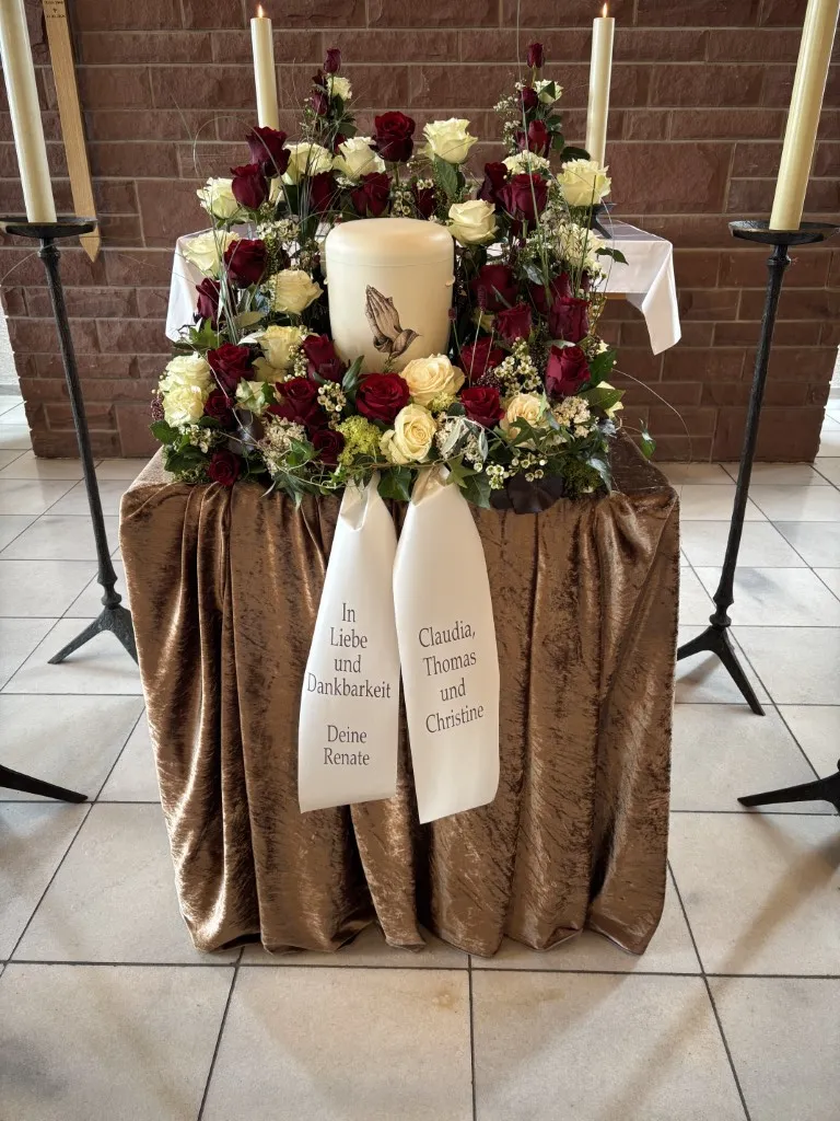 Urne umgeben von roten und weißen Rosen